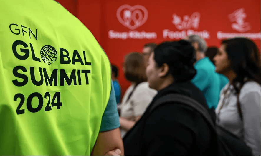 A person facing back wearing a vest with Global Summit 2024 logo