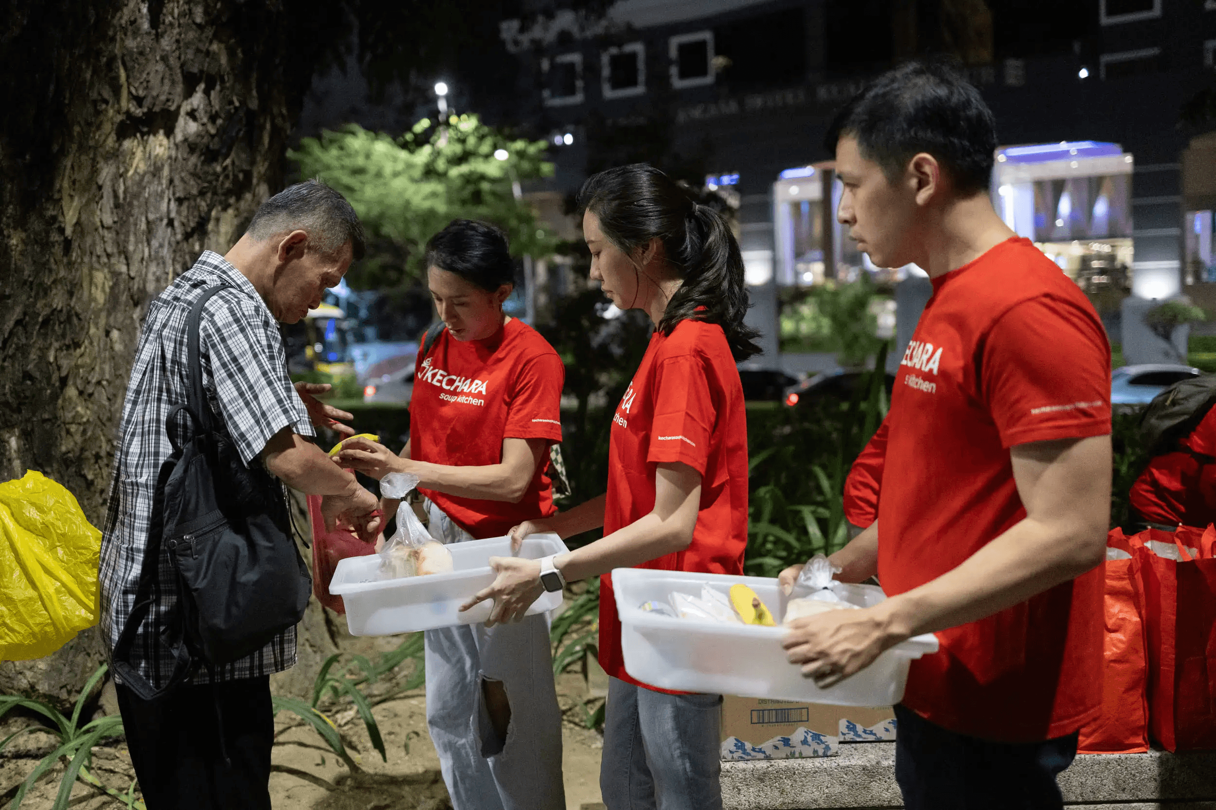 A volunteer presenting food pack to a beneficiary in a distribution event
