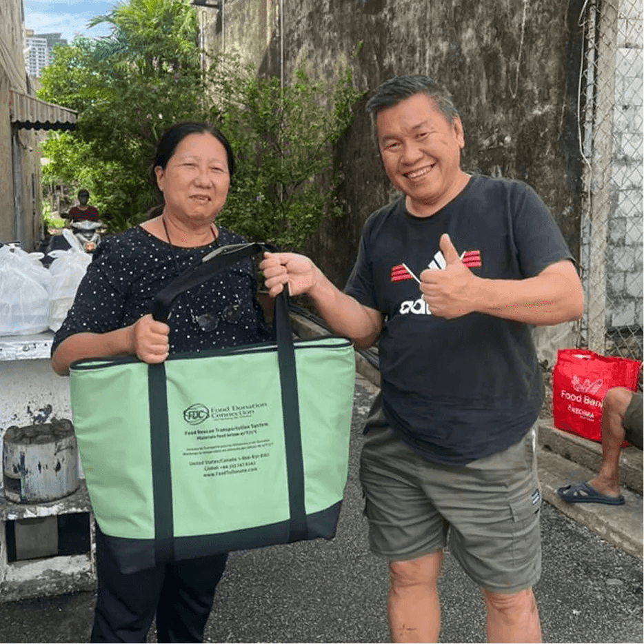 A volunteer presenting food pack to a beneficiary in a distribution event